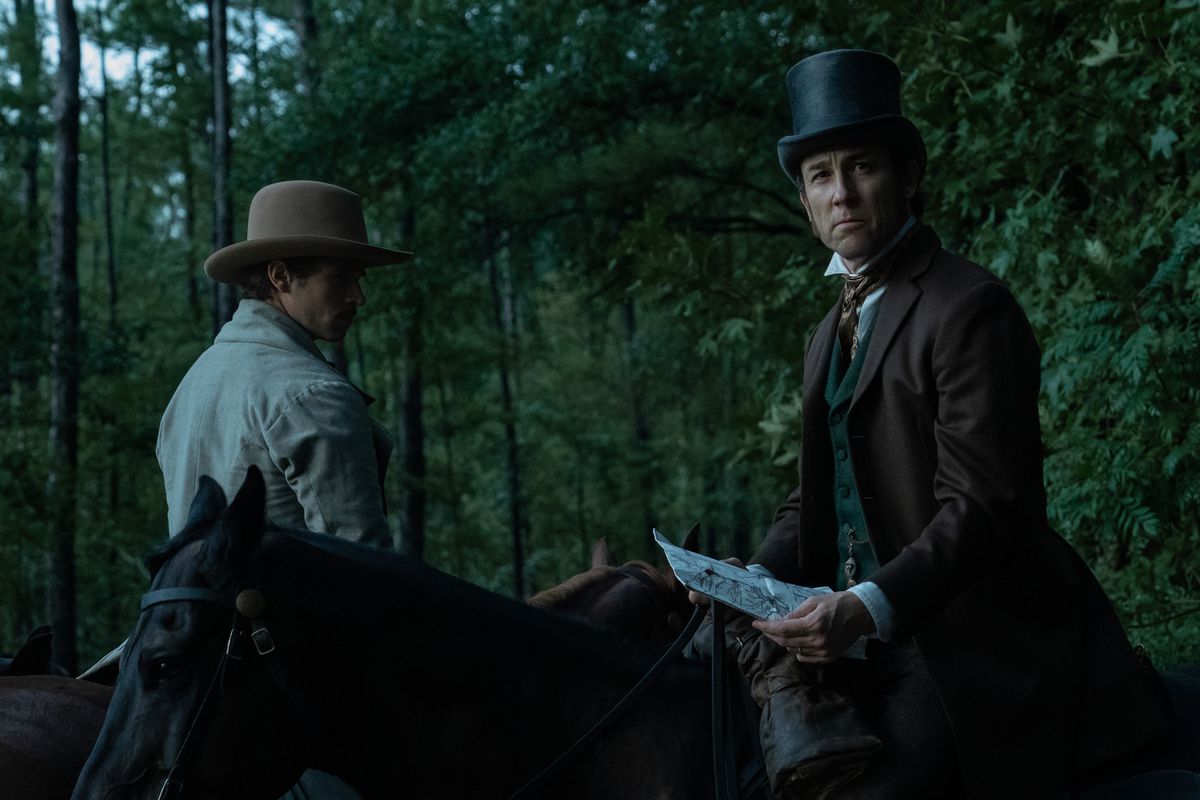 Stanton (Tobias Menzies) on the back of a horse in the woods looking inquisitively off-camera