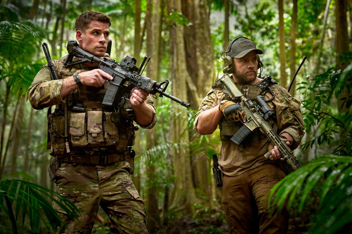 Liam and Luke Hemsworth hold assault rifles in military camo in Land of Bad