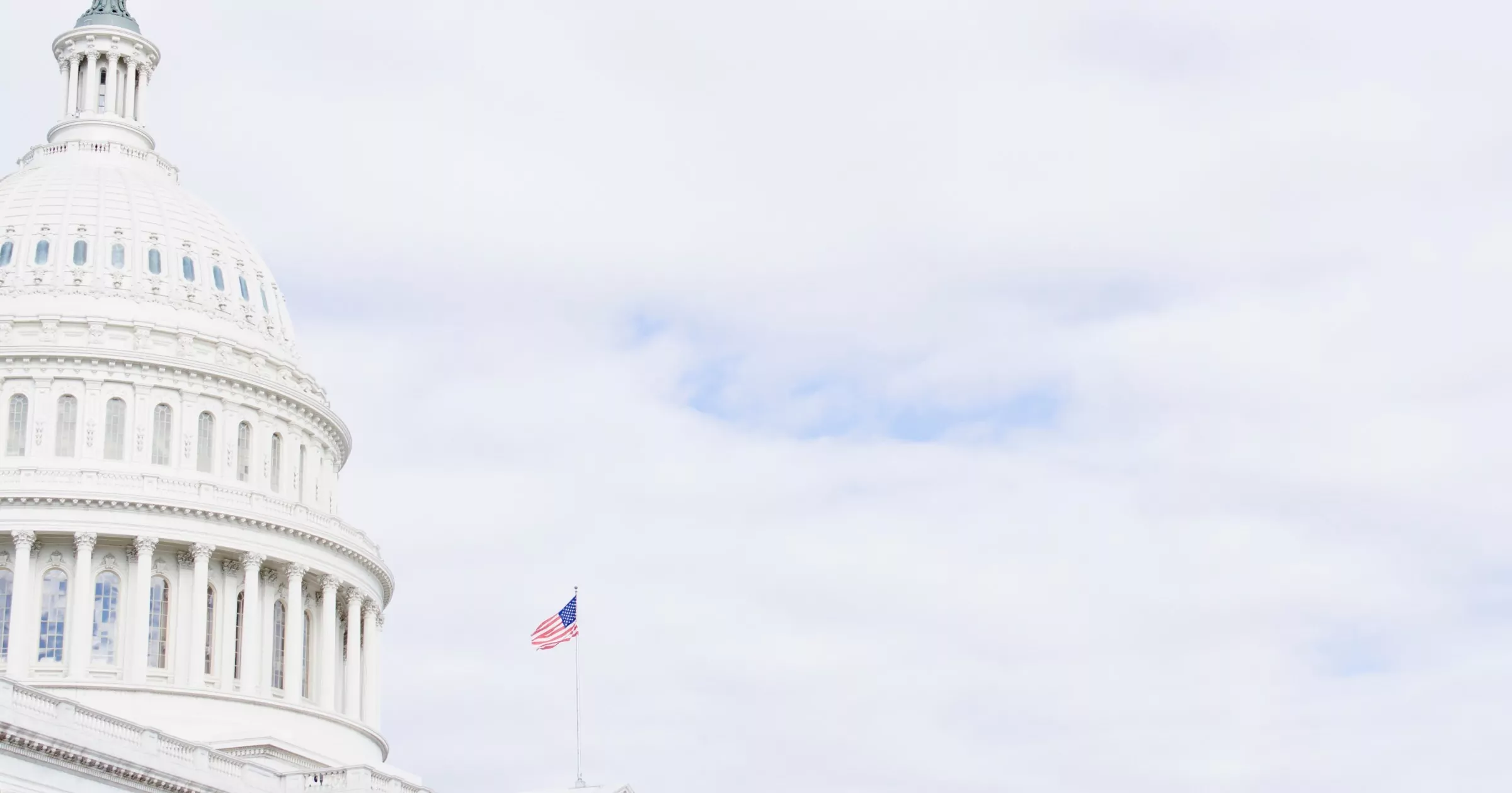 Picture of the US capital and an American flag in front of sky