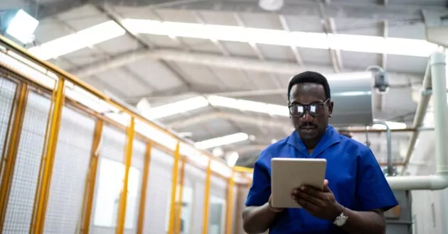 Man with glasses in a data warehouse looking at ipad