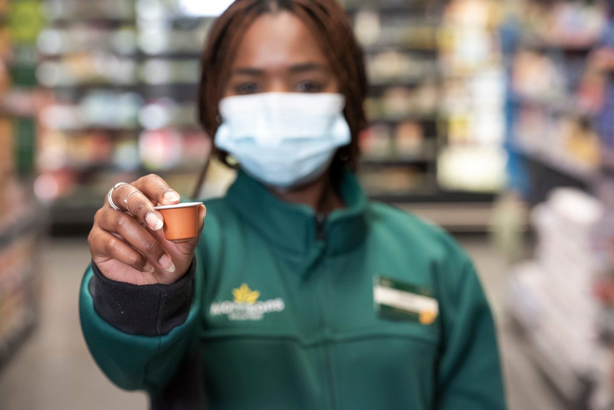 Morrison's supermarket employee holding out a coffee pod