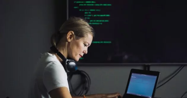 Person at laptop coding in dark room