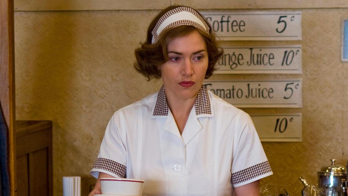 Kate Winslet stares off into the middle distance while wearing a waitress uniform in Mildred Pierce. She holds a coffee cup and behind her a sign advertises drinks for very, very low prices.