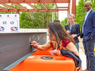 From left, College of Engineering dean Kim Needy signs a beam while Margaret Sova McCabe (vice chancellor for research and innovation) and Charles Robinson (chancellor) observe.