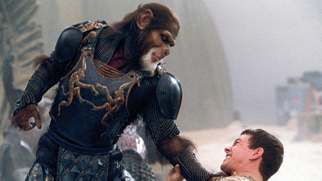 An leering anthropomorphic ape wearing elaborate armor holding down a struggling man in Planet of the Apes.