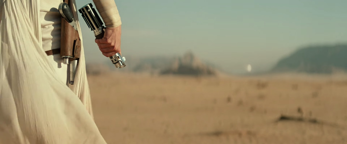 A shot of Rey wielding onto Luke’s lightsaber as enemies approach.